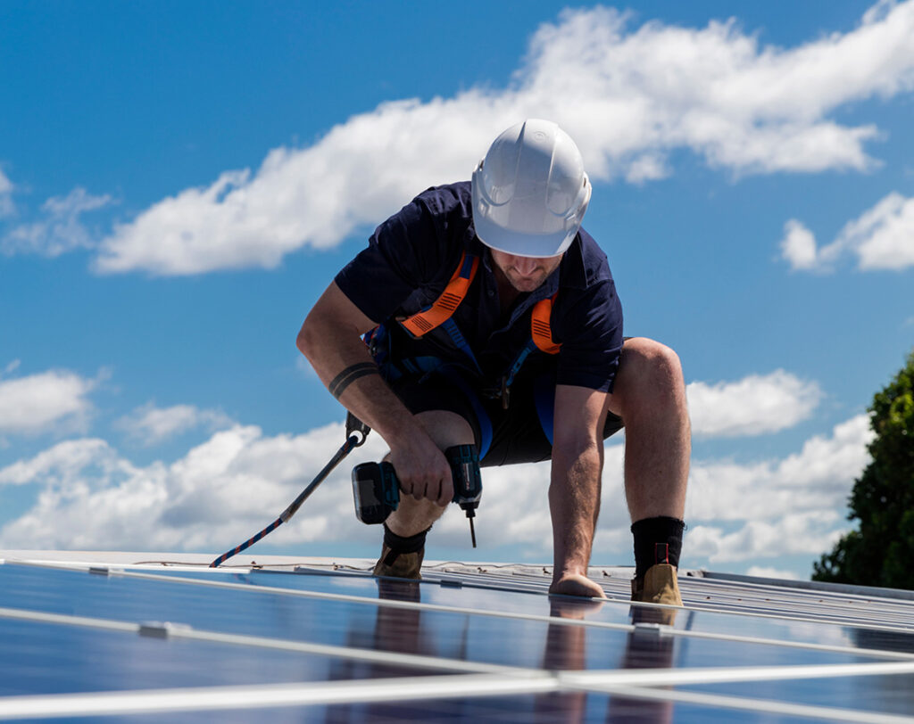 Fachmann auf dem Dach bei der Installation von Solarmodulen für eine Photovoltaik-Anlage